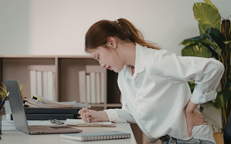 デスクワーク中に腰痛に悩む女性