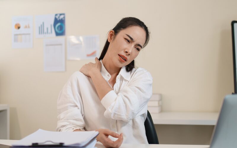 デスクワークで肩こりに悩む女性