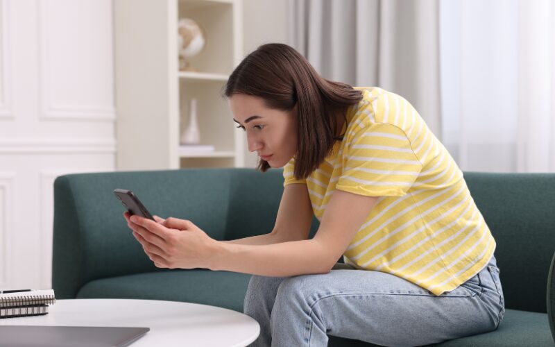 スマホを見て猫背になっている女性